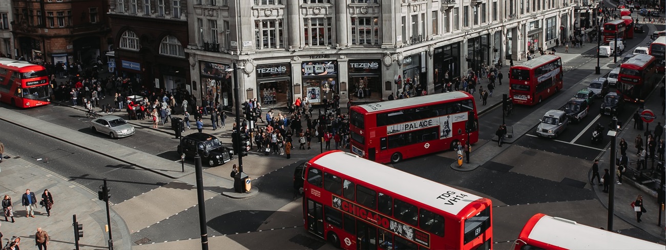 a group of people walking on a street with buses and people