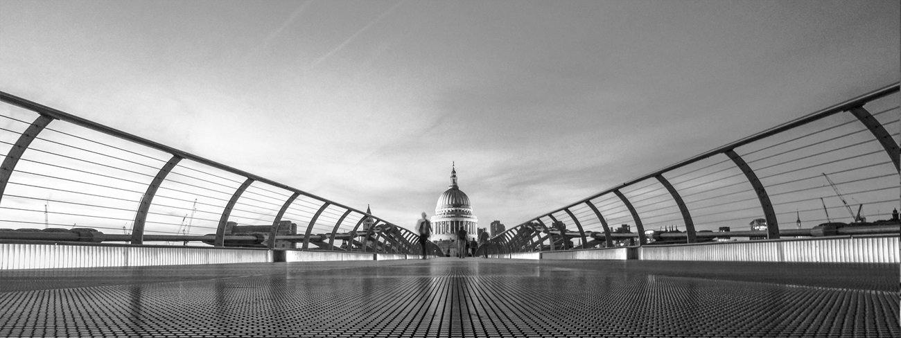 a black and white photo of a bridge with a person walking on it