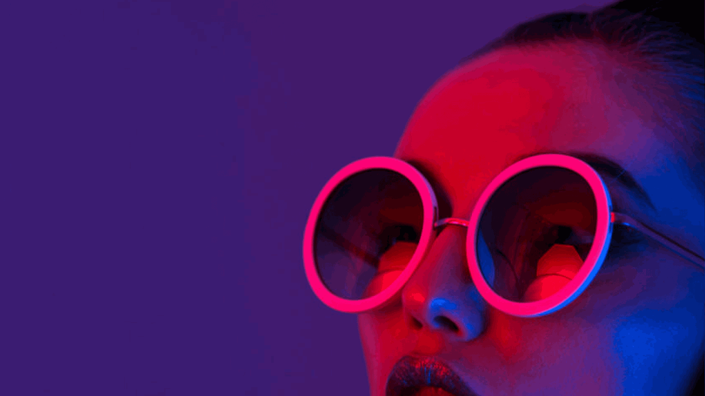 woman wearing round glasses in purple light