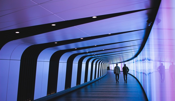 people walking on a walkway in a futuristic building